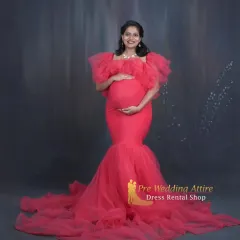 Celebrate your silhouette with this stunning red mermaid gown, designed to elegantly highlight your baby bump. The ruffled off-shoulder neckline and tulle train add a touch of glamour, making it perfect for a classic studio maternity session.
