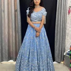 A stunning powder blue lehenga with silver mirror work. The cold shoulder blouse with tassel details makes it a modern and chic choice for a wedding guest.