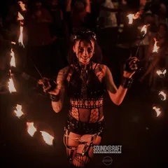 A female fire dancer smiles as she spins two sets of fire poi, surrounded by the glow. We believe in connecting with the audience, sharing the joy and energy of the performance.
