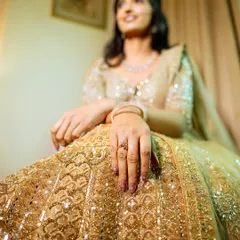 A detail-oriented shot focusing on the bride's intricate lehenga and engagement ring.