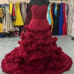 This wine-red ruffled gown is a showstopper. The strapless sweetheart neckline and dramatic, layered tulle skirt create a glamorous and unforgettable look, shown here on a mannequin in our showroom.