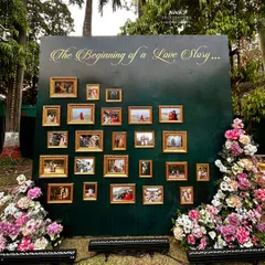 A beautiful memory wall titled "The Beginning of a Love Story," showcasing the couple's journey through framed photographs on a rich green backdrop.