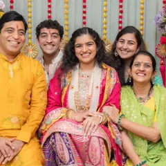 A lovely family portrait from the Bane Bithai ceremony. The bride is radiant in a multi-colored outfit, and her family is coordinated in bright, festive colors like yellow, green, and pink, creating a picture full of warmth and joy.
