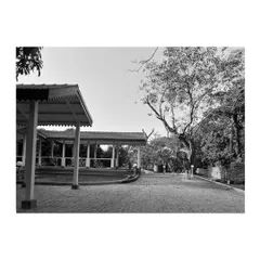 A black and white photograph capturing the timeless quality of the restored architecture. The clean lines of the pavilion and the aged cobblestone driveway create a resilient design that transcends generations.