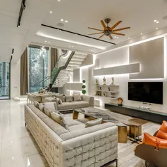 A view of the main living area in the Vikaspuri residence, showcasing a mix of comfortable seating, modern art, and custom lighting. The wall-mounted shelving and integrated TV unit keep the space feeling clean and uncluttered.