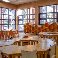 This classroom at Euro School, Bannerghatta, features hexagonal tables that can be reconfigured for group activities. The honeycomb-shaped storage units and large windows create a bright, adaptable, and nature-inspired learning environment.