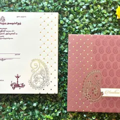 A traditional Tamil wedding invitation featuring a paisley motif. The text is beautifully printed in Tamil script on the envelope.