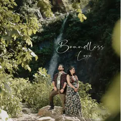 A majestic wide shot of a couple standing amidst lush foliage with a waterfall in the background, titled "Boundless Love."