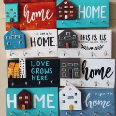A collection of our popular hand-painted keyholders. Each one is unique, featuring miniature houses and heartfelt quotes, making them a perfect personalized gift for a new home.