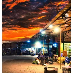A wide shot of the Phool Mandi at dusk, with a fiery orange sky contrasting against the illuminated market stalls. This image showcases our skill in landscape and architectural photography within a street setting.