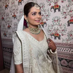 A happy bride in her elegant white ensemble. The makeup is subtle yet defining, with a focus on the eyes and a natural lip color.