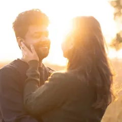 Bathed in the warm glow of the setting sun. Her hand gently touches his face as they share an intimate look. The backlight creates a beautiful halo effect, highlighting their connection.