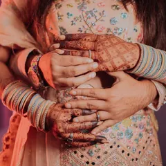 A creative close-up focusing on the couple's embrace and the details of their hands, showing the bride's bangles and the groom's ring.