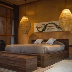 The bedroom of a premium suite, designed for ultimate comfort with a large bed, artistic decor, and direct access to nature.