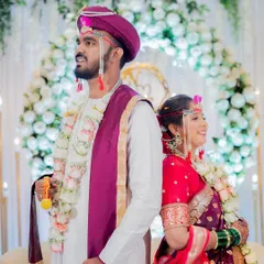A stylish back-to-back portrait of the bride and groom in their vibrant Maharashtrian wedding attire.