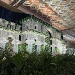 A grand architectural backdrop inspired by classic European conservatories. The structure is softened with lush greenery, creating a stunning setting for an elegant wedding.