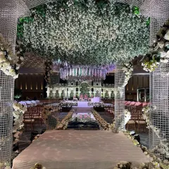 We create breathtaking entrances that transport guests into another world. This walkway, framed by a modern lattice structure and a ceiling of lush white and green florals, sets the stage for an enchanted garden wedding. 💚