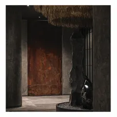 Another view of the grand copper door and the rock installation at the 'Frozen' entrance. The contrast between the warm, rusted metal and the cool, dark stone creates a powerful material dialogue that is central to the store's Zen-inspired theme.