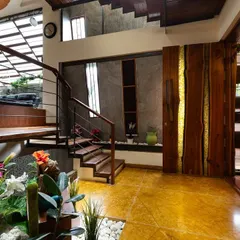 From the entrance, you can see the home's core materials at play. The warm tones of the oxidized flooring and the solid wood door, with its unique brass inlay, are balanced by the cool texture of the concrete wall and the greenery of the indoor garden.
