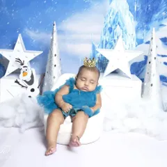 Even a sleeping princess fits perfectly in our Frozen theme. This photo shows the baby peacefully napping on a tiny white chair amidst the snowy, magical setting.