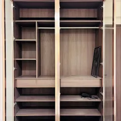 The interior of our glass profile wardrobe, revealing a thoughtfully organized space. It includes multiple hanging rods, deep shelves, and pull-out drawers, all crafted from high-quality wood laminate for durability and a premium feel.