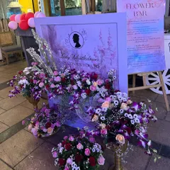 We brought a touch of Regency-era romance to this Bridgerton-themed baby shower. The welcome signage, featuring Lady Whistledown, is surrounded by lush arrangements of purple and pink orchids, roses, and baby's breath.