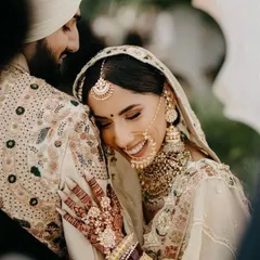 We believe your wedding photos should be full of joy, and your outfits should match that feeling. This couple is coordinated in beautiful ivory and cream tones. The bride's lehenga features delicate embroidery, complemented by the groom's matching sherwani, creating a soft, elegant, and modern wedding look.