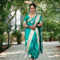 A full-length portrait of a bride in a stunning teal Nauvari saree. Her confident pose and direct gaze make this a powerful and elegant image, showcasing traditional bridal fashion.