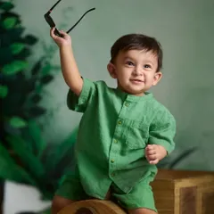 A cool and confident pose. Using simple props like sunglasses, this little boy shows off his personality during his indoor, jungle-themed photoshoot.