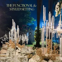 A glamorous and functional tablescape. Tall crystal candelabras create a stunning centerpiece, casting a warm, flickering light over the mirrored tabletop and elegant place settings.
