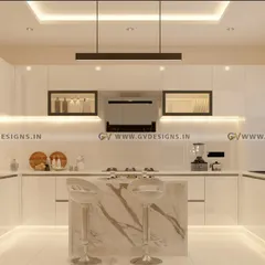 A pristine, all-white U-shaped kitchen designed for a clean and contemporary look. The space includes an island with a marble-finish base, lift-up glass shutters, and sleek G-profile handles, all illuminated by linear hanging lights.