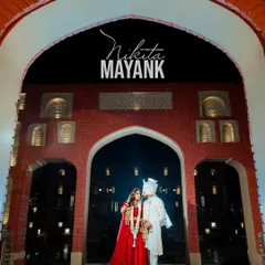 A stunning wide shot of the couple framed within the grand archway of the Noor Mahal Palace, capturing the scale and royalty of their wedding entrance.