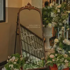 A closer view of the elegant welcome mirror. The reflection shows the surrounding floral decor, creating a layered and beautiful welcome for guests arriving at the wedding.
