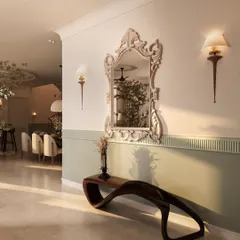 The entry foyer of this penthouse sets a dramatic tone with a two-toned green and white wall, a striking classical mirror, and a sculptural wooden bench. It's a grand welcome that hints at the home's blend of modern and classical styles.