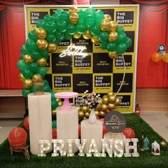 A birthday setup for a client named Priyansh at The Big Buffet. This decor includes a circular balloon arch, themed pedestals, and large marquee letters spelling out the name on a turf mat.