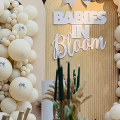 The custom 'Babies in Bloom' signage adds a personalized and stylish touch to the neutral-toned, fluted backdrop.