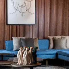 A closer look at the vertical wood panelling, showing the clean lines and warm tones that bring a timeless quality to the space. The texture of the wood contrasts beautifully with the cool blue of the sofa.