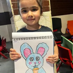 This little artist is so proud of her bunny drawing, and she should be. We focus on making art fun and rewarding, encouraging creativity with every colorful sketch.