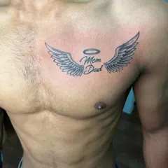 A classic "Mom Dad" tribute tattoo with angel wings and a halo. This chest piece is a popular way to honor parents.