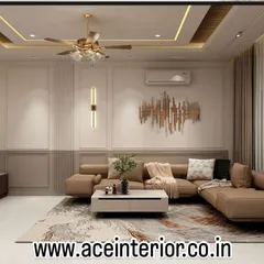 A contemporary living room featuring a neutral color palette, a comfortable L-shaped sofa, and striking gold accents in the wall art and ceiling. The false ceiling with cove lighting adds a layer of warmth and sophistication.