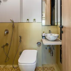 A compact bathroom design featuring geometric yellow floor tiles, a marble-finish vessel sink, and a space-saving vanity.