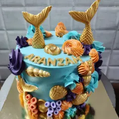 An enchanting mermaid-themed cake perfect for a magical birthday. This custom cake is decorated with golden mermaid tails, colorful buttercream corals, and delicate seashells.