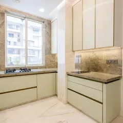 A view of the main cooking area, featuring a gas hob set on a beautiful Brazilian stone countertop. The soft sage green PU-finished cabinets and profile glass shutters create a light and modern feel.
