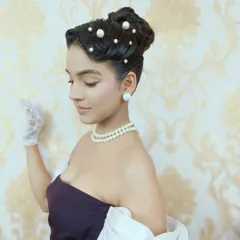 A side profile of the pearl-studded vintage updo. This angle showcases the sculpted waves and the careful placement of each pearl, highlighting the precision required for detailed period hairstyling.
