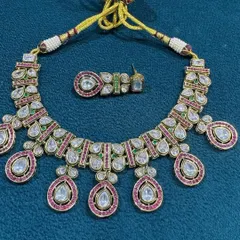 This polki kundan necklace set showcases large, clear uncut stones set in a traditional design with pink stone accents. It is a versatile piece that can be worn by the bride or her family.