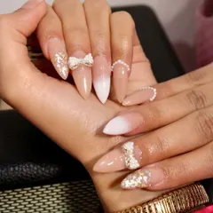 Unleash your inner diva with these pearl and bow embellished nails. This set combines a soft ombré base with delicate 3D bows, scattered pearls, and gold glitter for a luxurious finish.