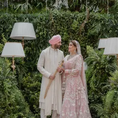 An elegant portrait of a Sikh couple during their Anand Karaj ceremony, set against a lush green backdrop.