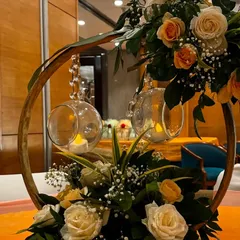 A rustic yet elegant centerpiece from an event at Jaypee Siddharth. The design uses a wooden ring, hanging candle orbs, and a beautiful arrangement of peach and white roses.