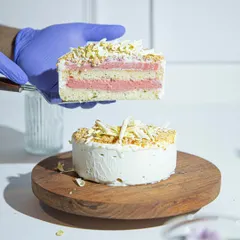 A slice of our Vanilla Raspberry ice cream cake held aloft, showcasing the beautiful pink and white layers. This is what pure, handcrafted goodness looks like.
