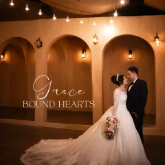 'Grace Bound Hearts'. A stunning wide shot showcasing the bride's beautiful gown and the romantic ambiance of the venue.